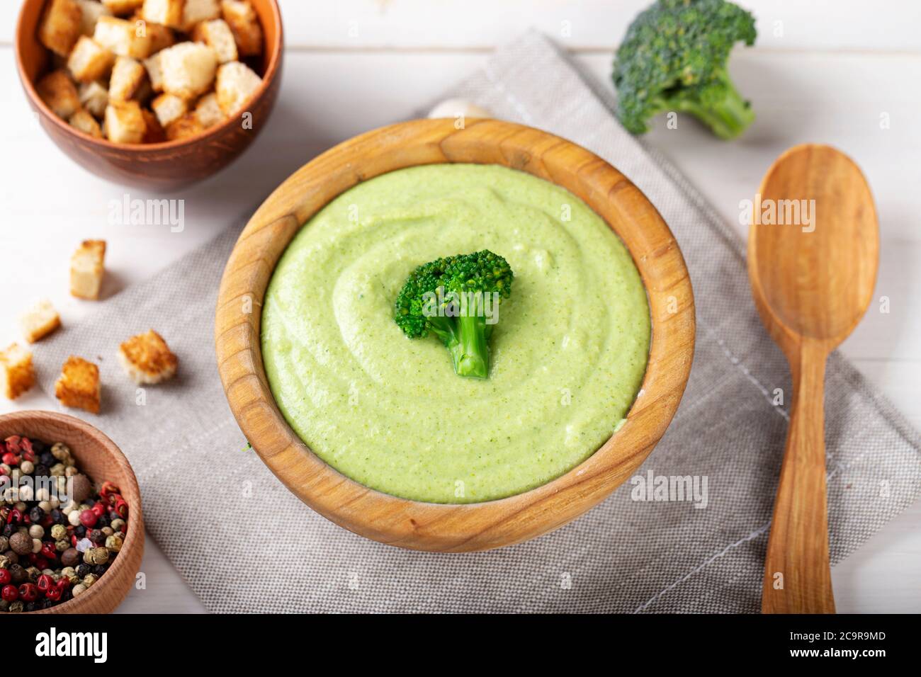 Grüne Brokkoli-Sahne Gemüsesuppe in einem Holzteller auf dem Tisch. Suppe mit Brokkoli Blütenstand verziert Stockfoto