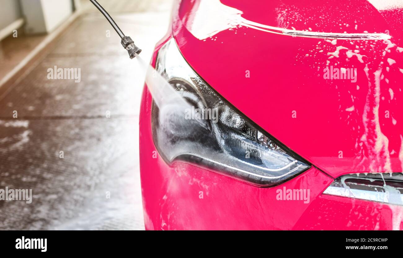 Nahaufnahme der Front Licht von hellen rosa gewaschen in self serve Autowäsche, Hochdruck-Wasser sprühen auf das Glas Stockfoto