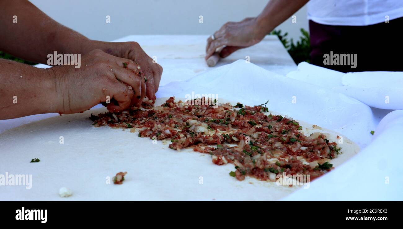 Türkische Küche, türkische Küche: Gözleme. Eine menschliche Hand bedeckt den Teig mit der Füllung. Es gibt eine Hackfleisch- und Gemüsefüllung Stockfoto