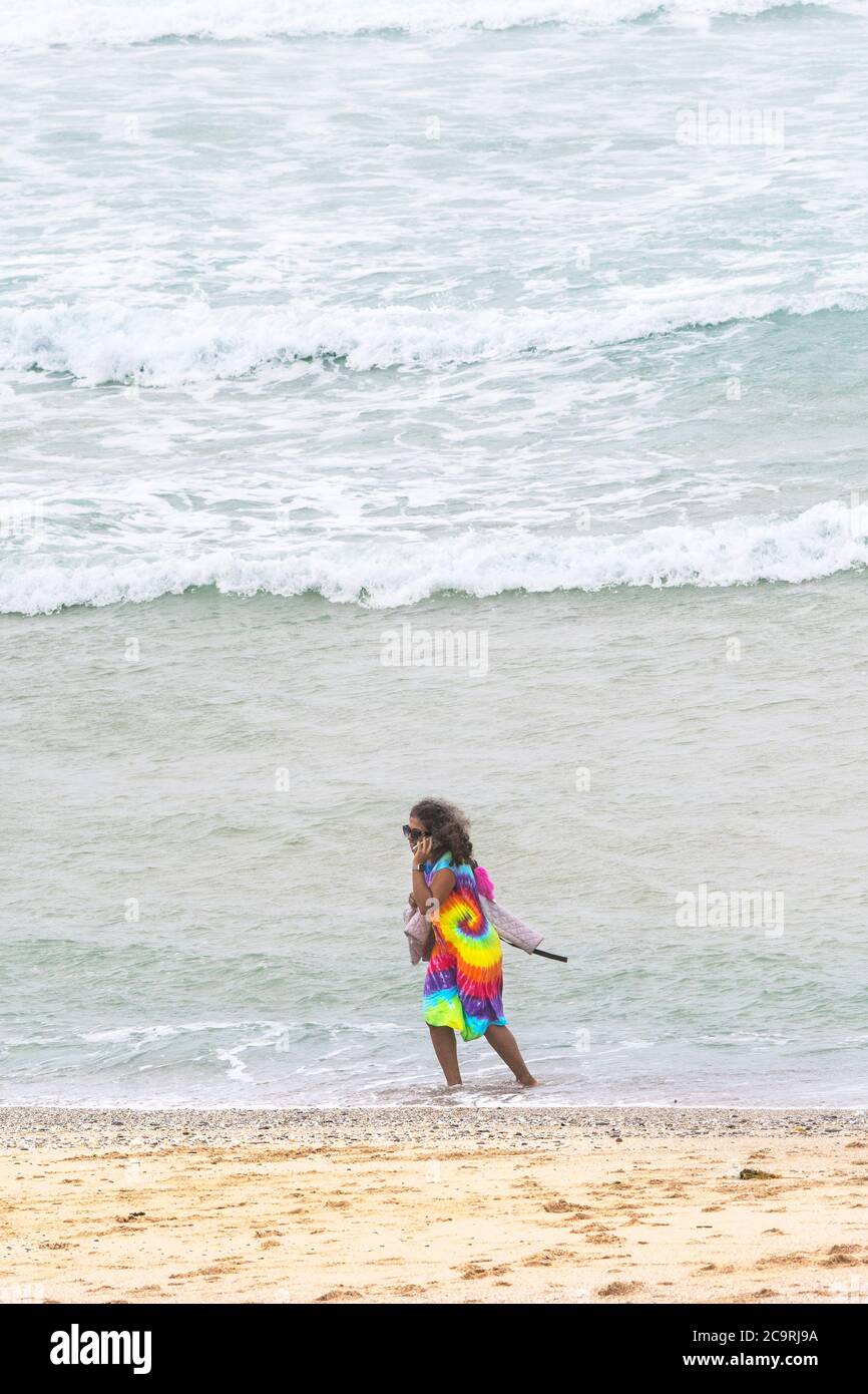 Ein Urlauber in einem farbenfrohen Kleid, der an der Uferlinie am Fistral Beach in Newquay in Cornwall steht. Stockfoto