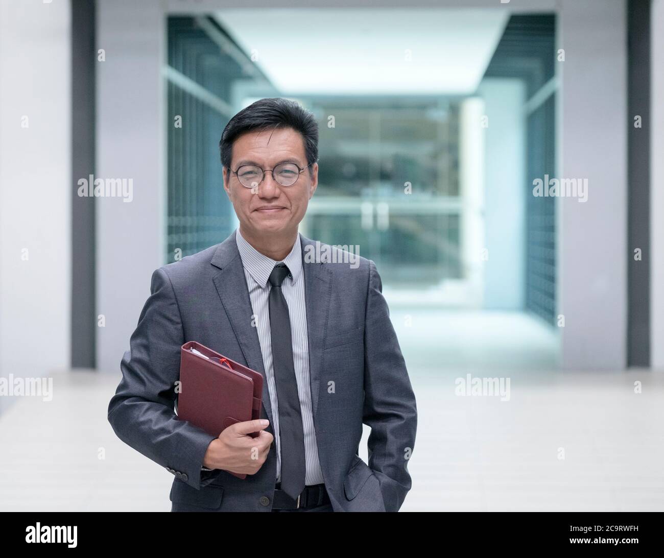 Porträt eines lächelnden chinesischen Geschäftsmannes in Krawatte und Business-Anzug mit einem Tagebuch, Blick auf die Kamera. Stockfoto