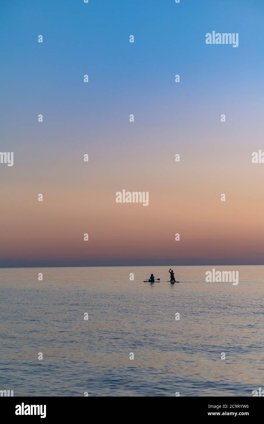 Paddle Boarding Paar am Lake Michigan kurz nach Sonnenuntergang, Sleeping Bear National Lakeshore, Michigan Stockfoto