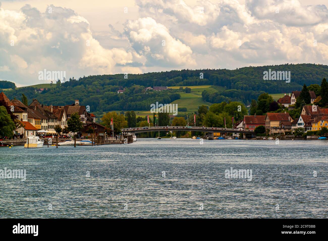 Stein am Rhein, Schweiz 05/28/2010: Blick auf den Rhein und die Rheinbrücke. Bild zeigt alte Häuser am Flussufer, kleine Boote, ein bewaldeter Stockfoto