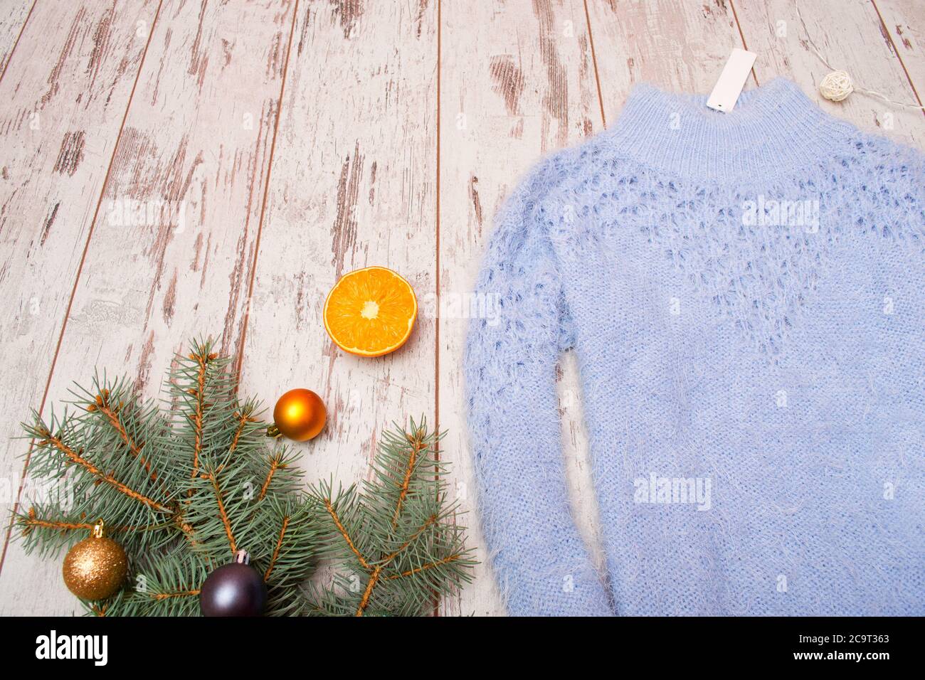 Weihnachtskonzept blau gestrickter Pullover mit Anhänger, Fichtenzweig mit Ornamenten, orange. Leerzeichen für Text Stockfoto