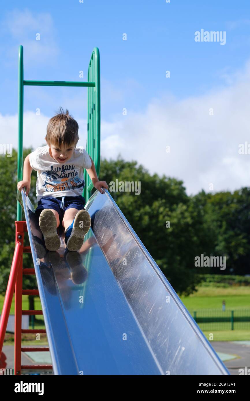 Vierjähriger Junge auf einer Rutsche auf dem Spielplatz Stockfoto