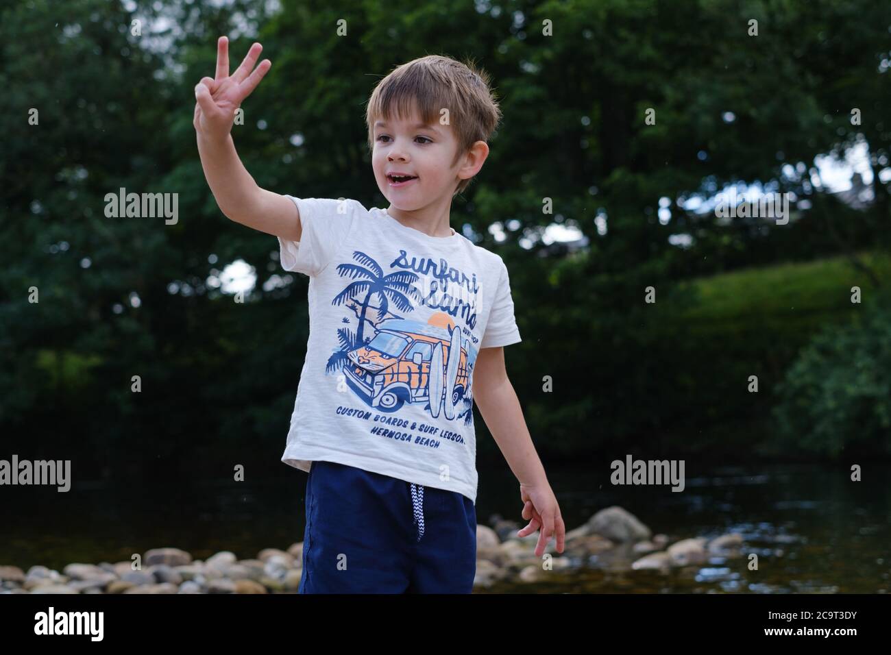 Vier Jahre alter Junge neben Strom hält drei Finger Stockfoto
