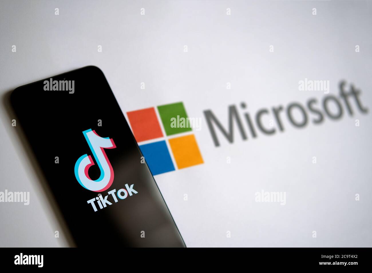 Stone / UK - 2. August 2020: TikTok App auf dem mobilen Bildschirm und Microsoft-Logo auf dem Papier zu sehen. Selektiver Fokus. Stockfoto
