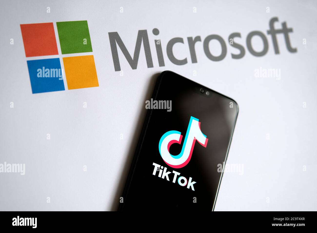 Stone / UK - 2. August 2020: TikTok und Microsoft Deal Konzeptfoto. TikTok App auf dem mobilen Bildschirm und Microsoft-Logo auf dem Papier zu sehen. Hauptfokus Stockfoto