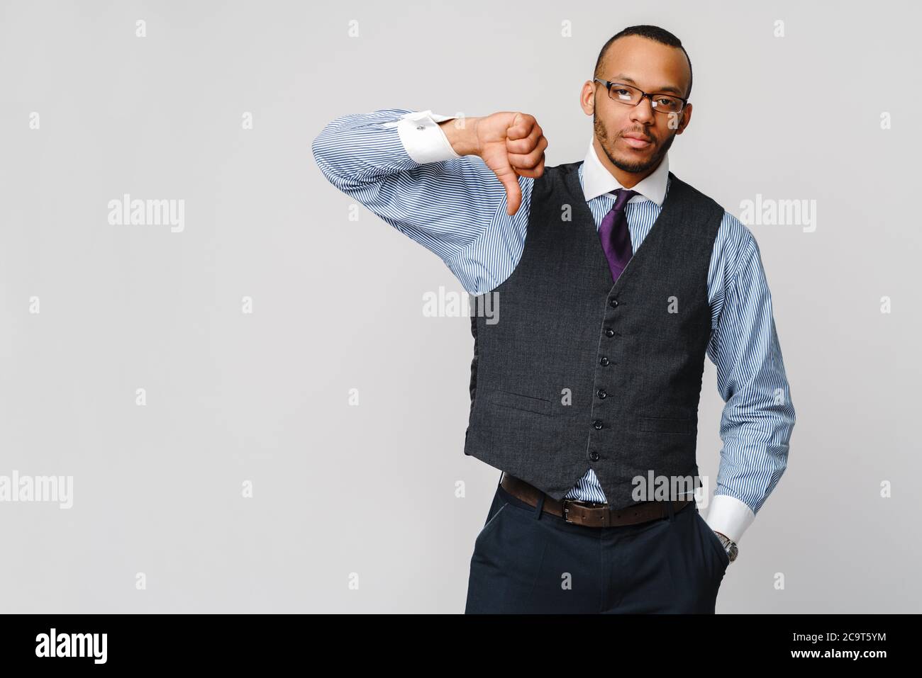 Junger schwarzer Geschäftsmann mit einem widerwärtiger ernster Abneigung gegen den Ausdruck mit Daumen nach unten in Missbilligung Stockfoto
