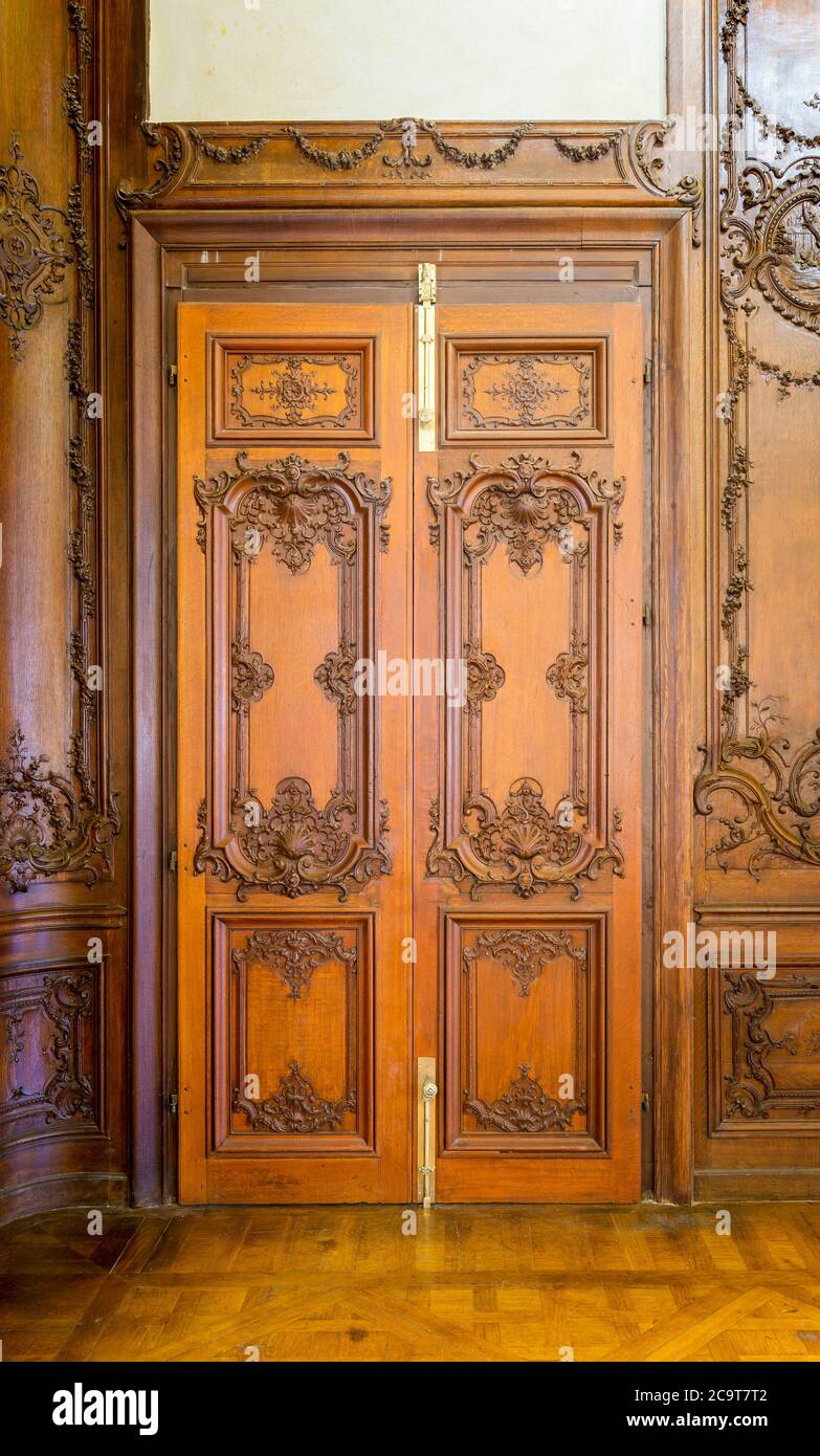Geschlossene elegante Holztür mit gravierten Dekorationen, installiert in hölzernen dekorativen Torbogen führt zu altem Gebäude Stockfoto