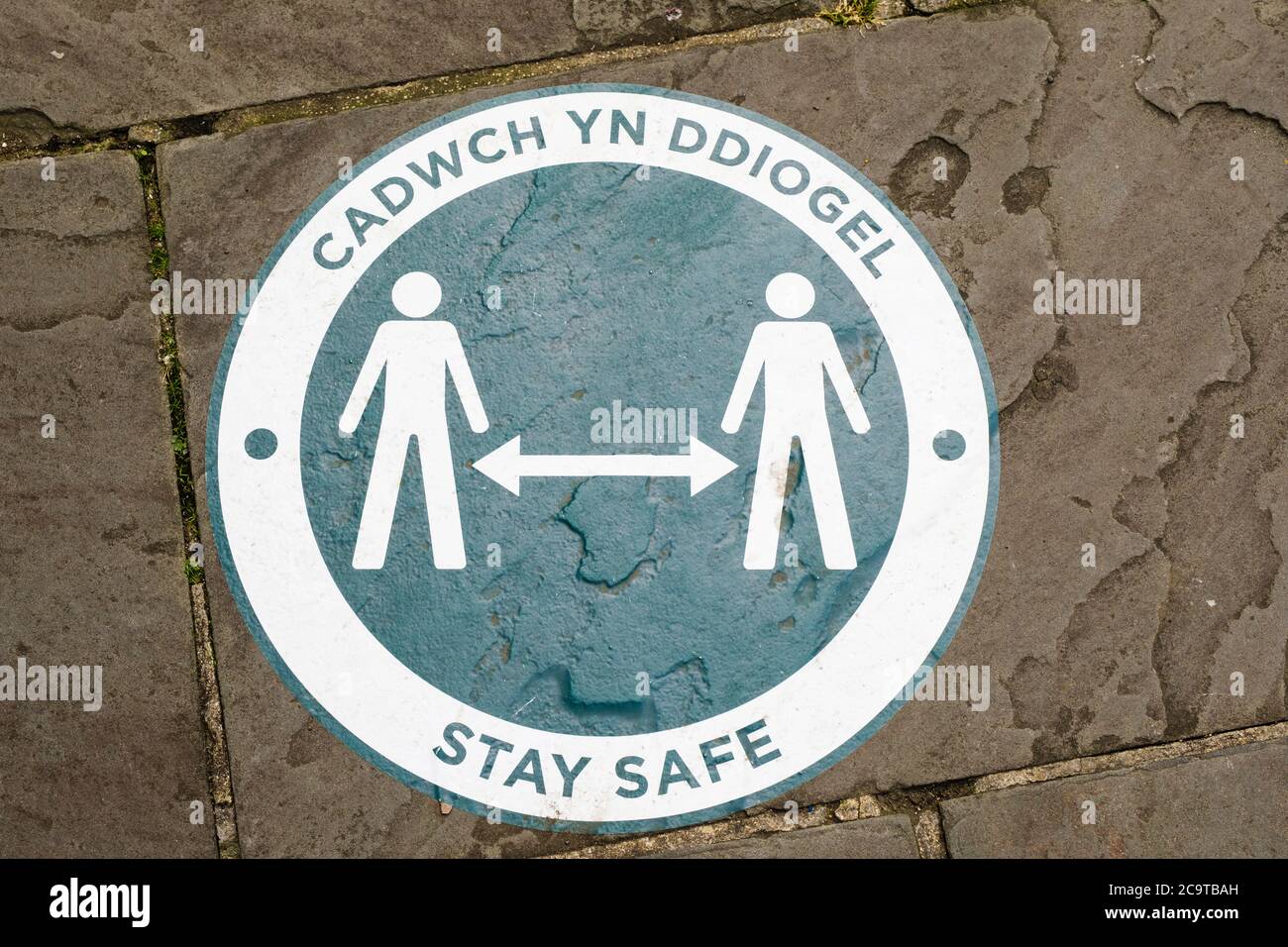 Bilingual Welsh English Stay Safe Social Distancing Zeichen für Covid-19 Coronavirus Pandemie im Jahr 2020 auf einem Bürgersteig in der Stadt Chepstow Wales Großbritannien Stockfoto