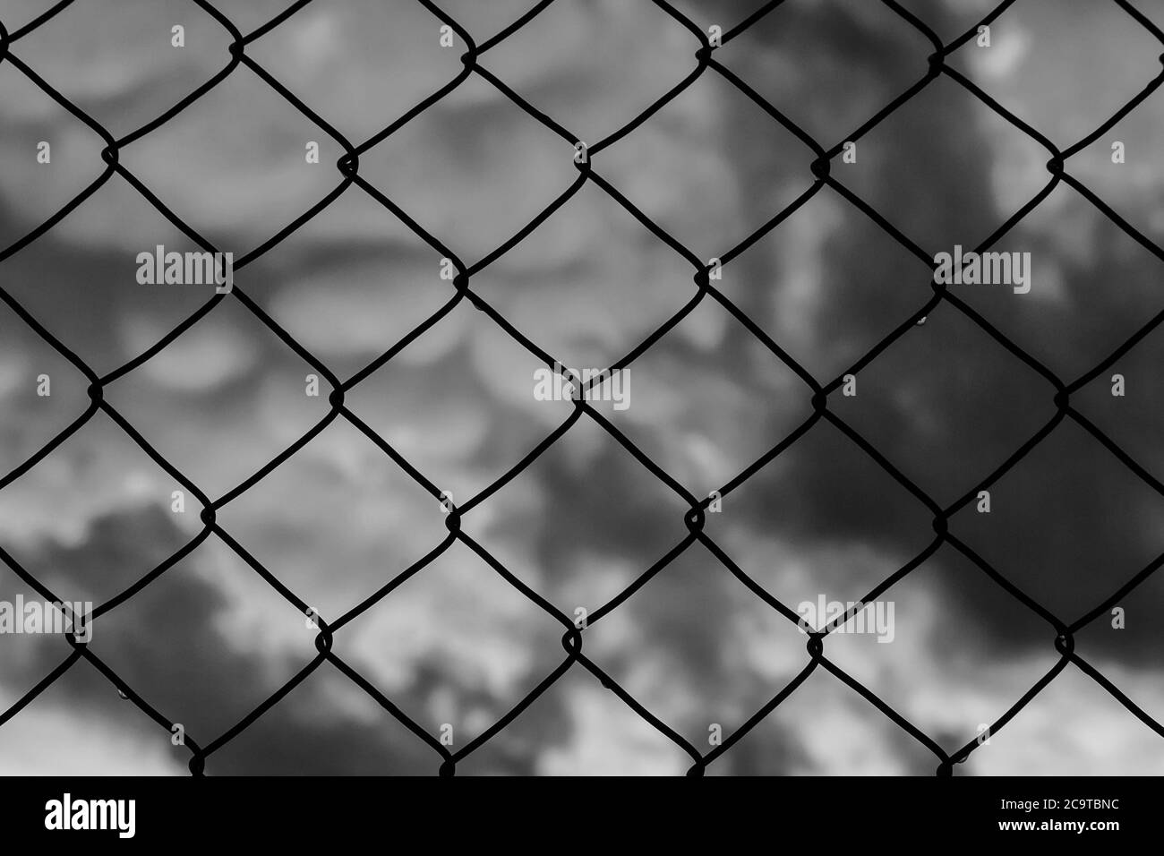 Gitter mit verschwommenem Himmel hinter dem Hintergrund (Schwarz und Weiß) Stockfoto