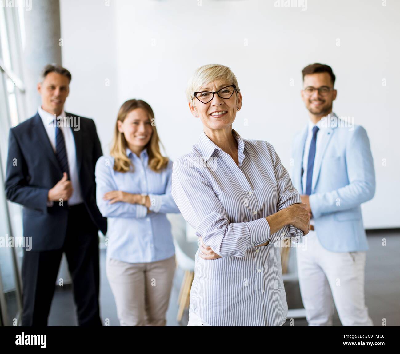 Gruppe von Geschäftsleuten, die zusammen im Büro mit ihrer reifen weiblichen Geschäftsführerin stehen Stockfoto