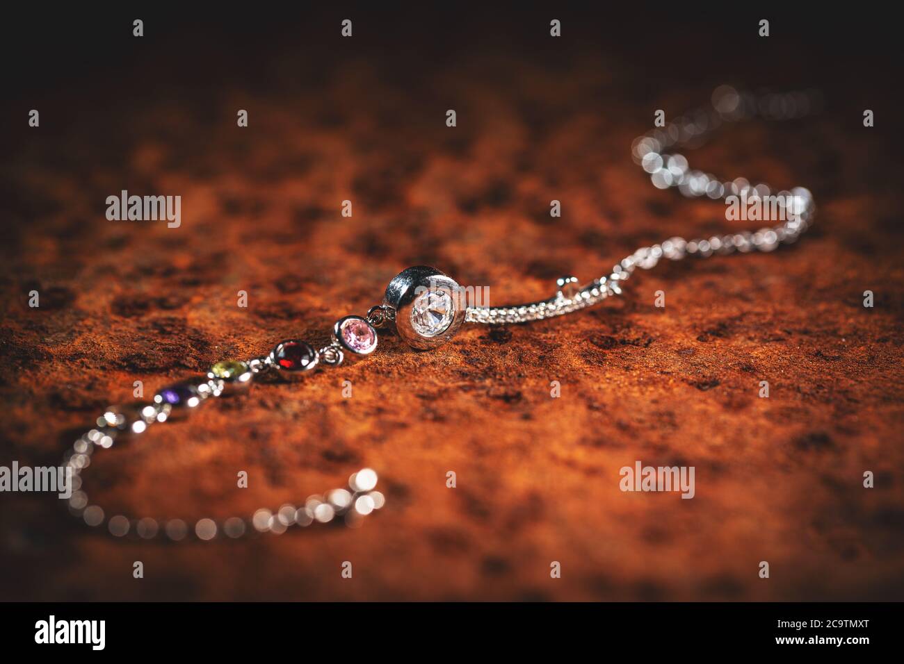 Silberne Halskette mit bunten Kristallen auf braunem Hintergrund Stockfoto