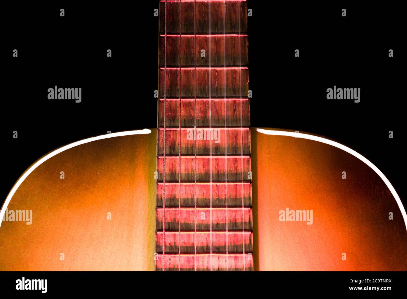 Akustikgitarre Soundboard mit Teil des Griffbretts und beleuchtet mit rotem Licht von unten Stockfoto