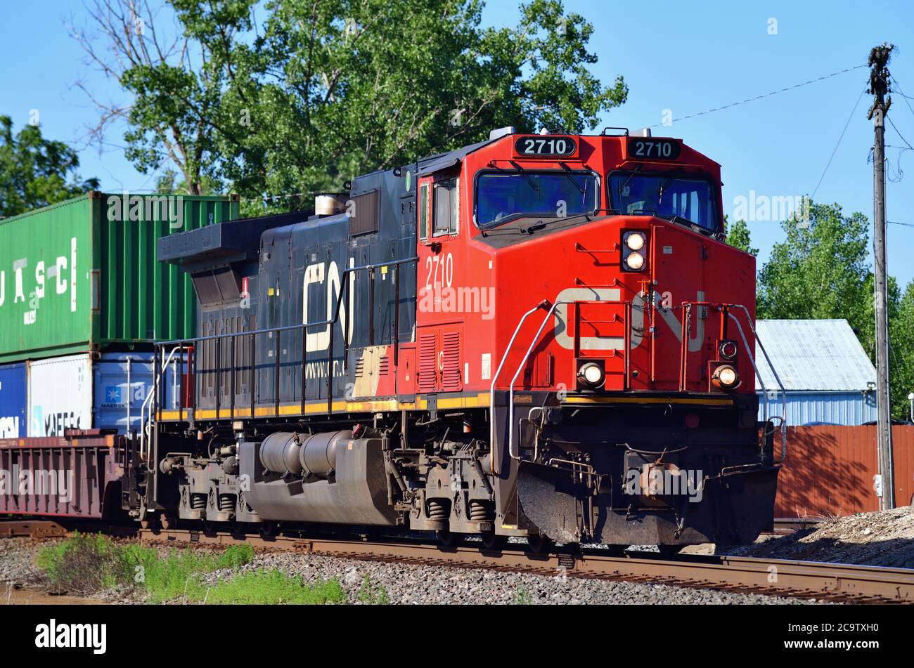 Bartlett, Illinois, USA. Eine einzige Canadian National Railway Lokomotive führt einen intermodalen Güterzug durch eine Kreuzung. Stockfoto