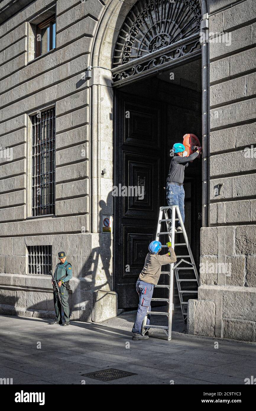 Madrid, Spanien - 20. Mai 2020: Zwei Arbeiter stellen eine Kamera in einem offiziellen Gebäude mit einer Leiter. Stockfoto