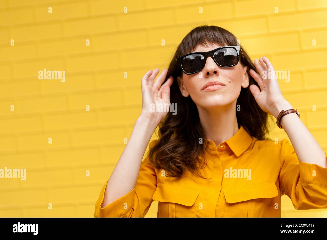 Porträt eines Mädchens in Sonnenbrille an der gelben Wand. Leerer Ort zum Schreiben von Text. In voller Länge Körpergröße Foto schön erstaunlich sie ihre dunkle Haut l Stockfoto