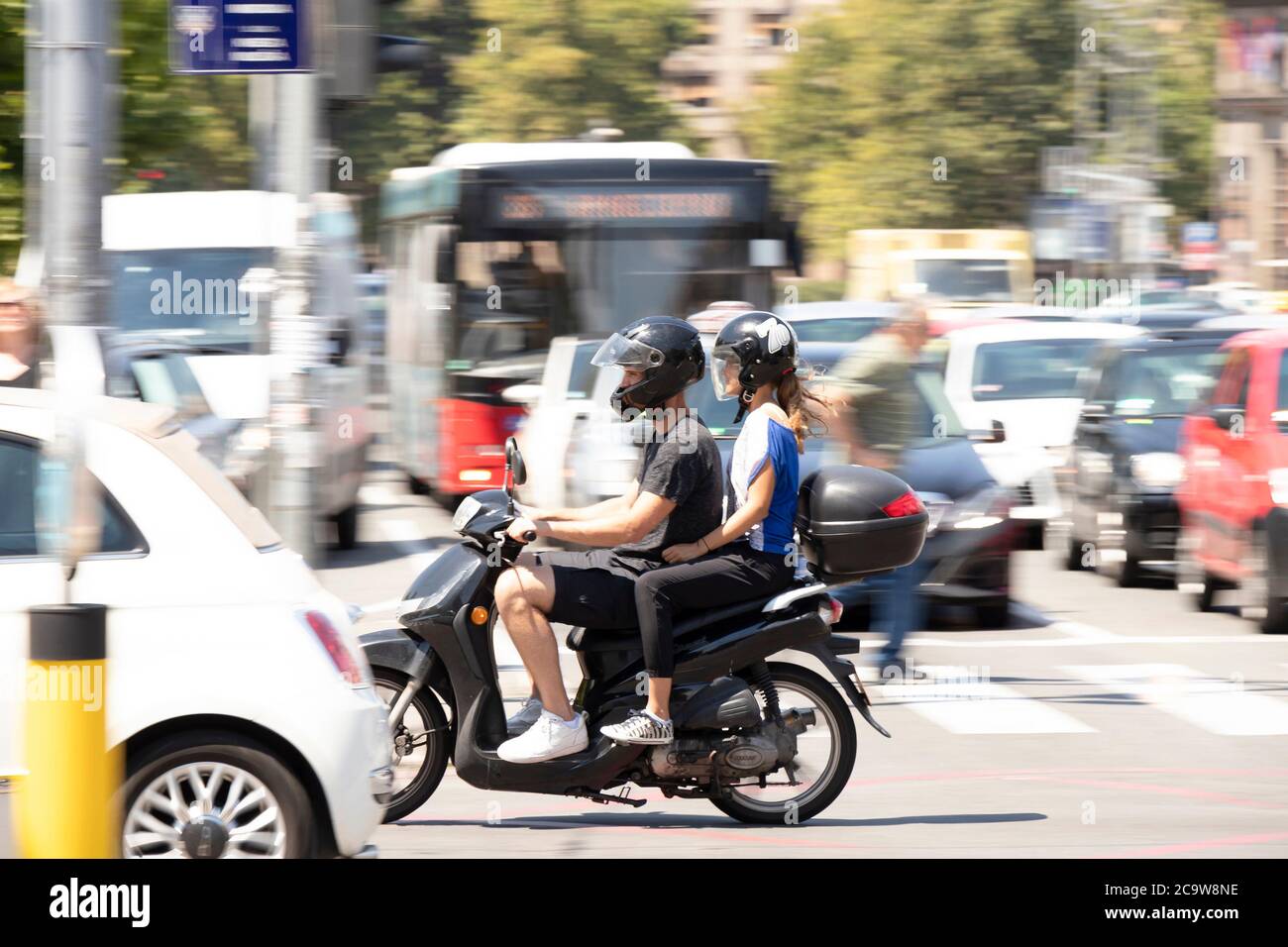Belgrad, Serbien - 21. Juli 2020: Junges Paar auf einem Roller vespa Motorrad im belebten Stadtverkehr, auf der Kreuzung mit Menschen und Autos Stockfoto