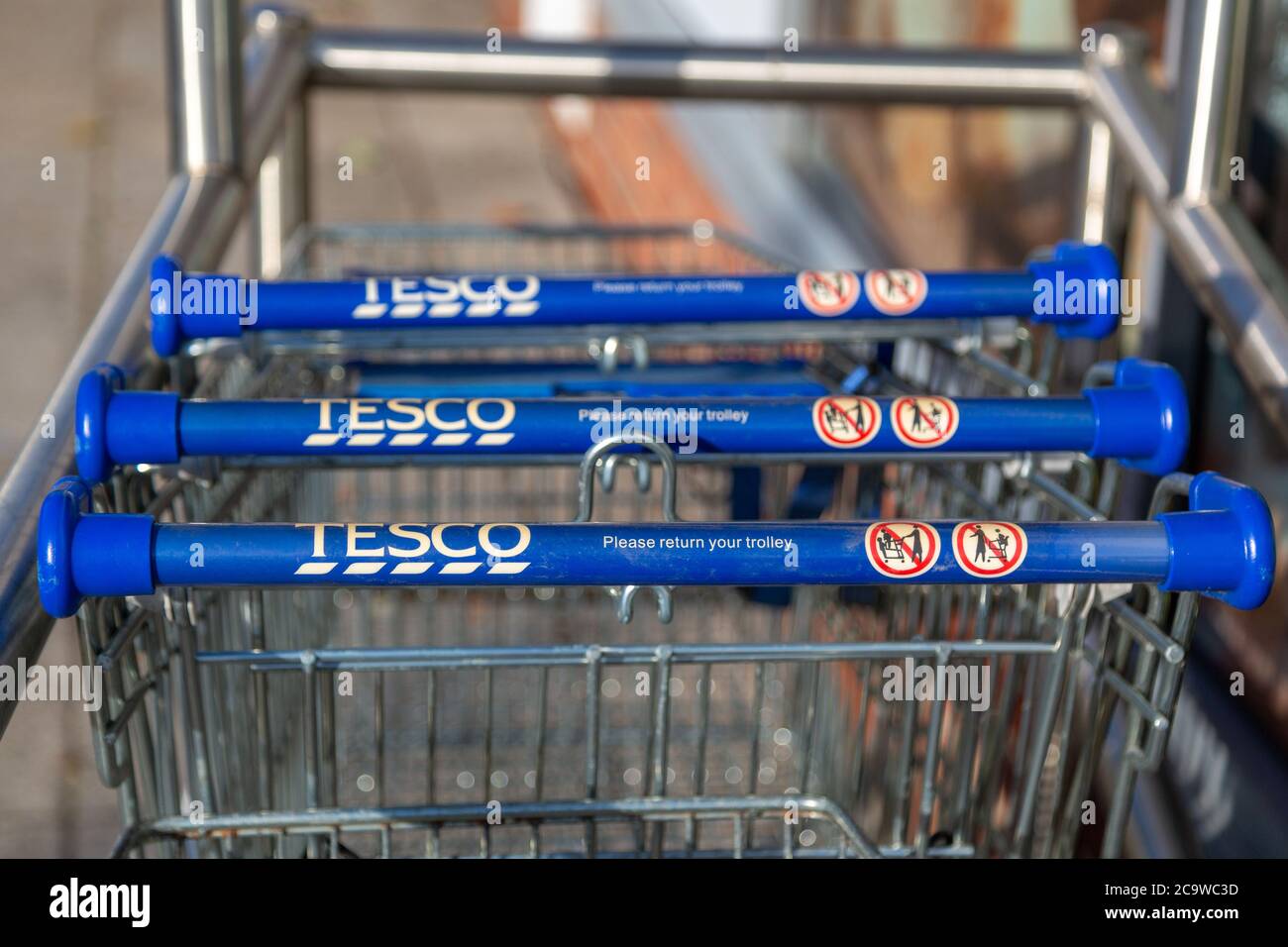 Eine Nahaufnahme der Griffe von Tesco-Einkaufswagen oder -Trolleys in einem Trolley-Park Stockfoto
