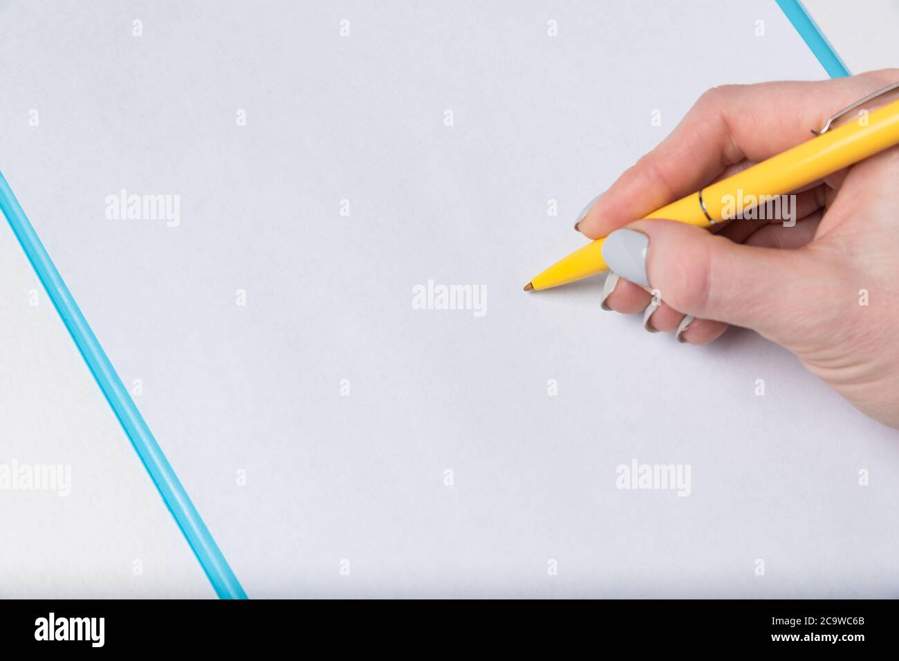 Weibliche Hand mit Stift auf einem leeren Blatt Papier. Frau legt Unterschrift auf Papier. Nahaufnahme. Stockfoto