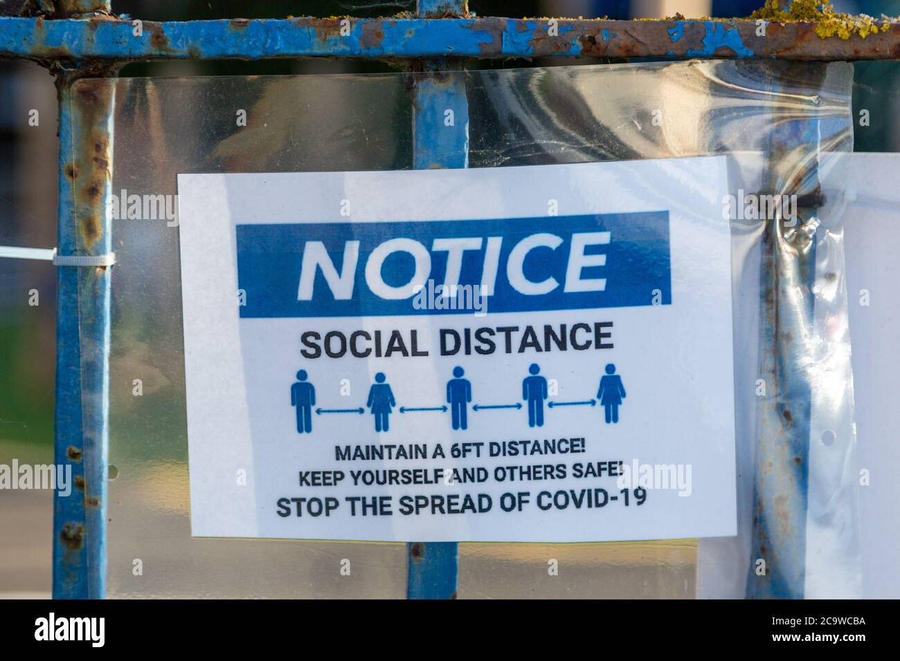 Ein Hinweis auf einem Zaun, in dem die Regeln für die soziale Distanzierung während des Coronavirus oder Covid-19-Ausbruchs gemäß den Richtlinien der Regierung angegeben sind Stockfoto