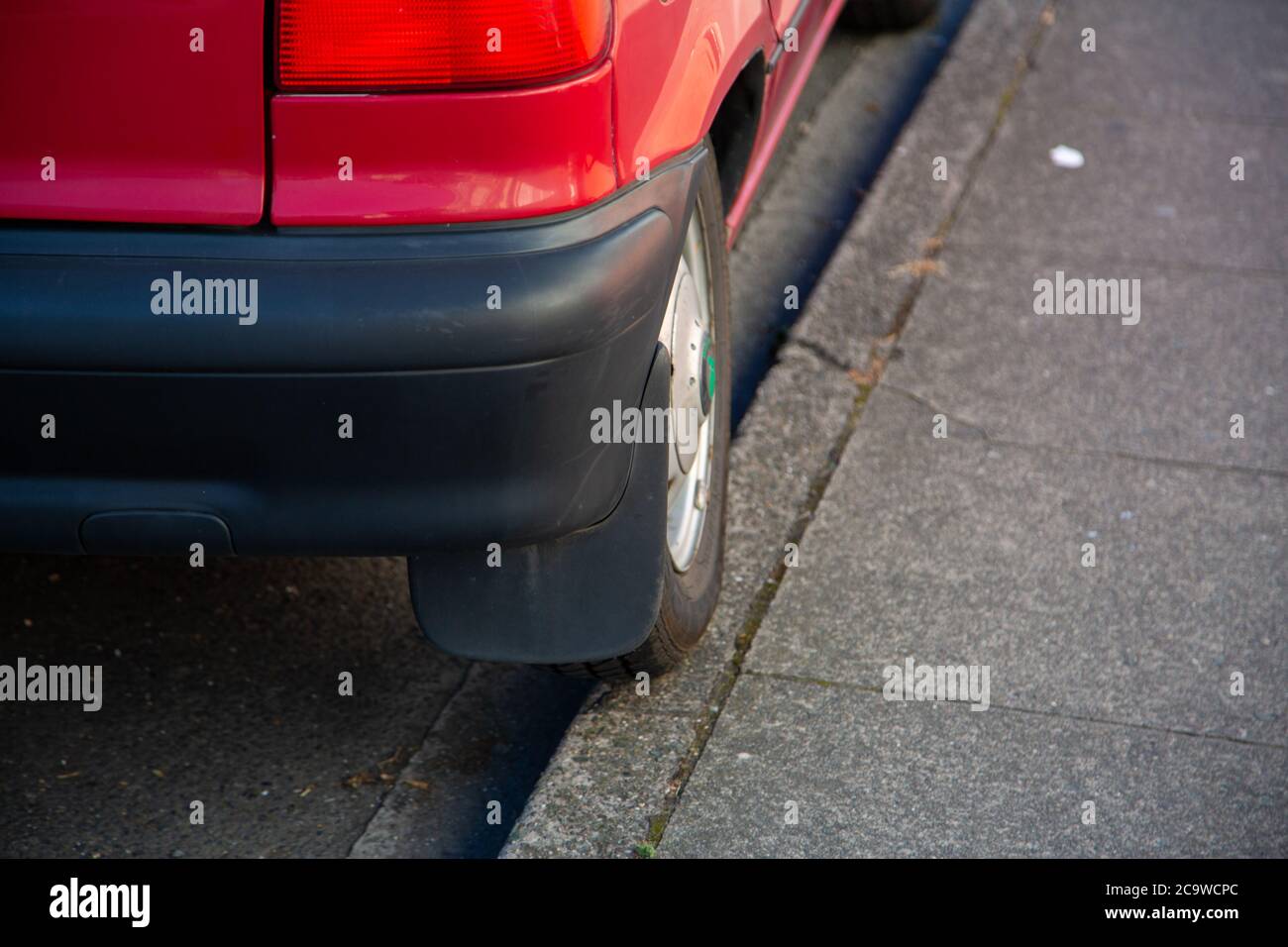 Das Rad eines schlecht geparkten Autos parkte auf einer Bordsteinkante Stockfoto