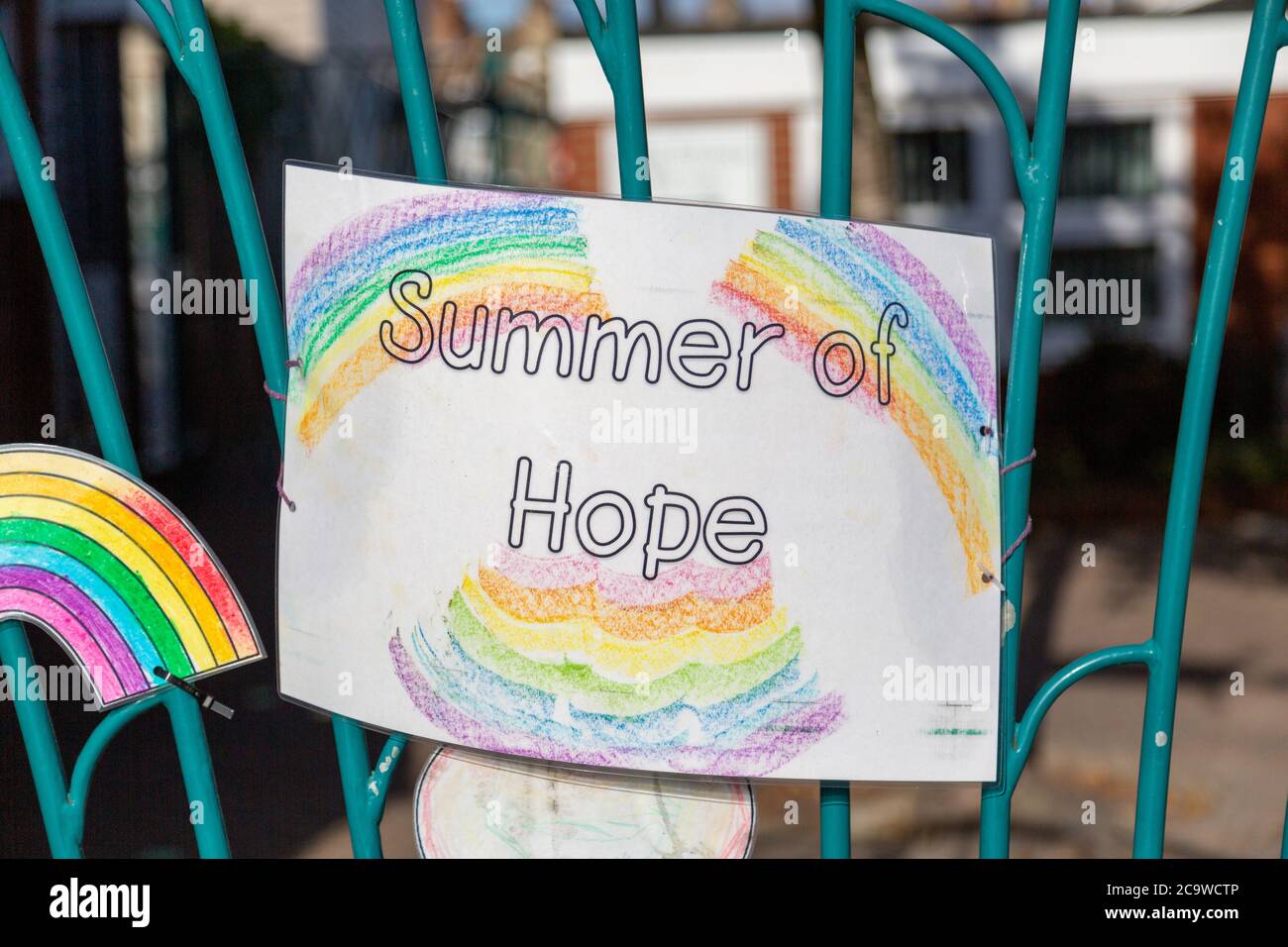 Eine Kinderzeichnung auf einem Schultor mit Regenbögen und Summer of Hope geschrieben darauf während der Coronavirus Pandemie Stockfoto