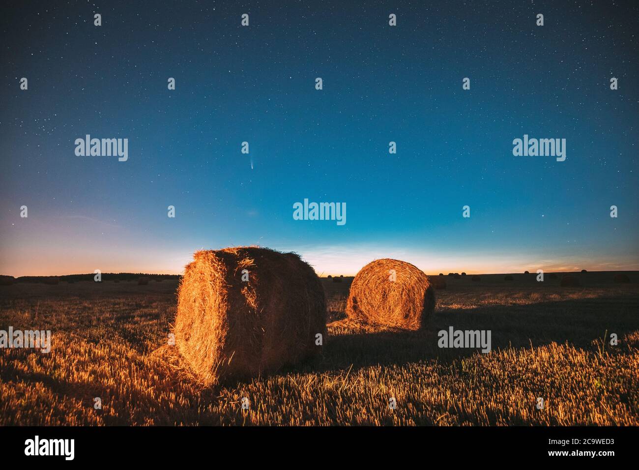 Komet Neowise C2020 F3 in Nacht Sternenhimmel über Haystacks im Sommer landwirtschaftlichen Feld. Nachtsterne Über Der Ländlichen Landschaft Mit Heuballen Nach Stockfoto