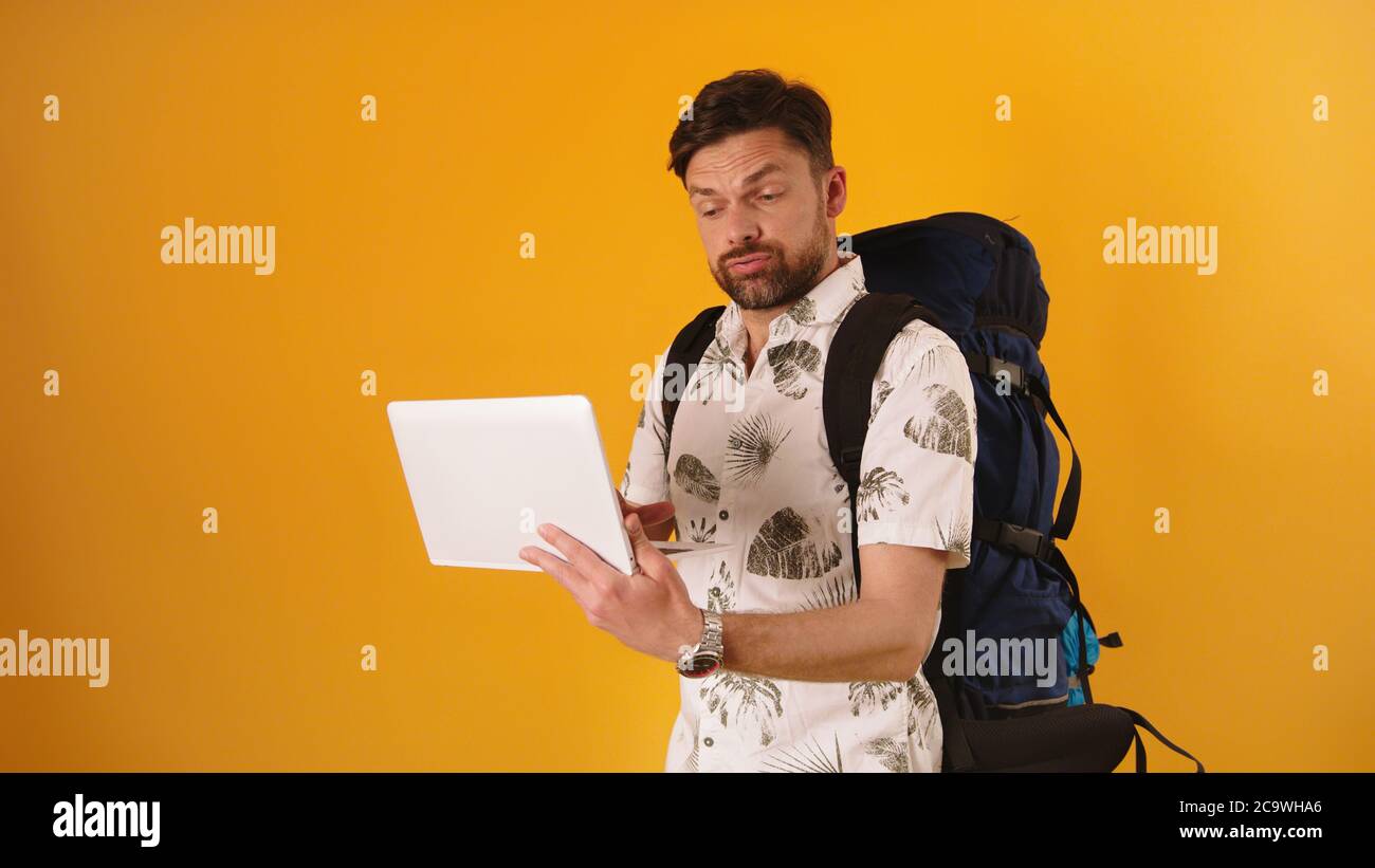 Junger Mann mit Rucksack Kamera und Blick verloren oder überrascht. Navigation mit modernen Geräten Konzept. Hochwertige Fotos Stockfoto