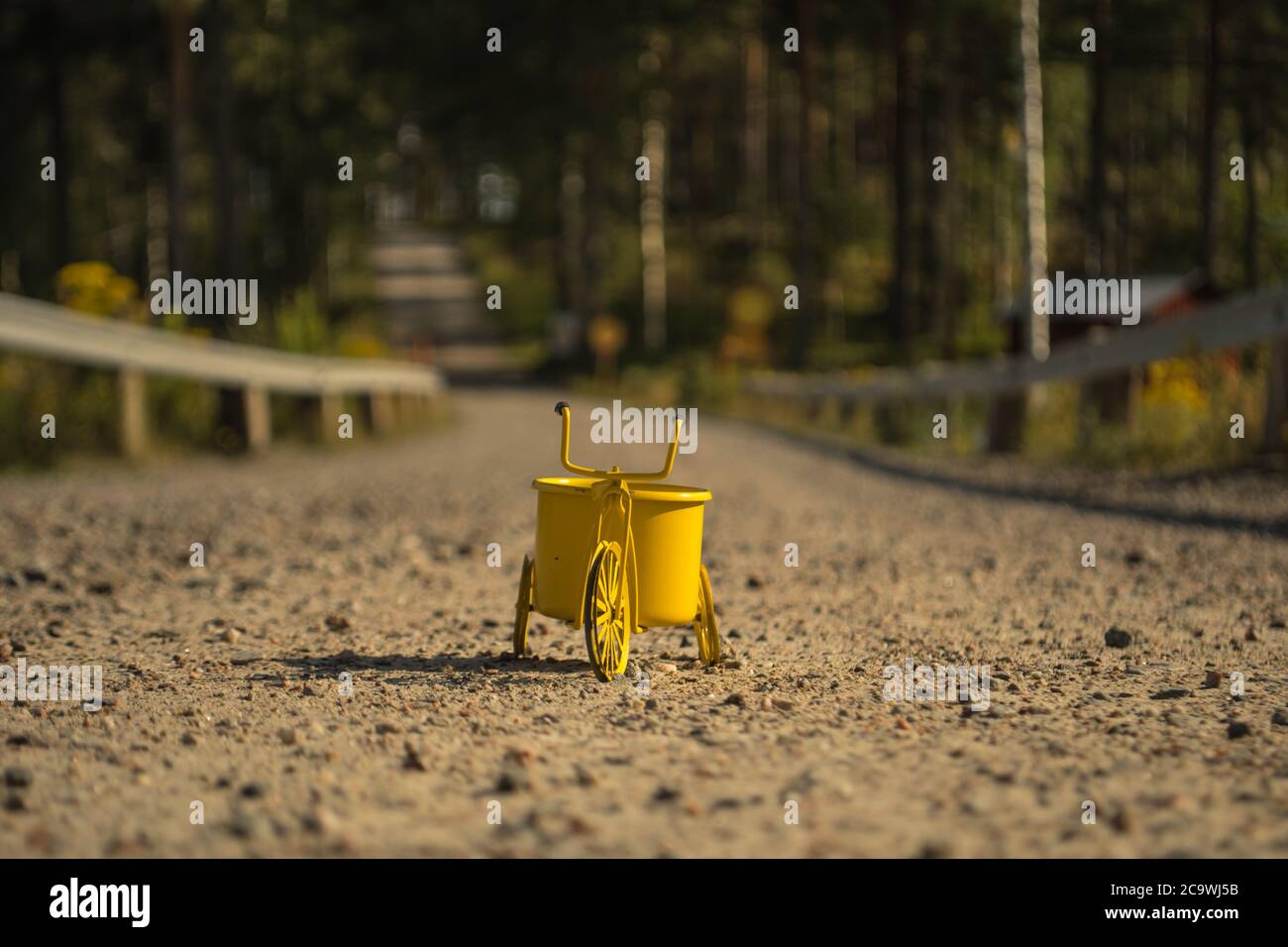 Ein gelbes Spielzeug-Dreirad auf einer Schotterstraße Stockfoto