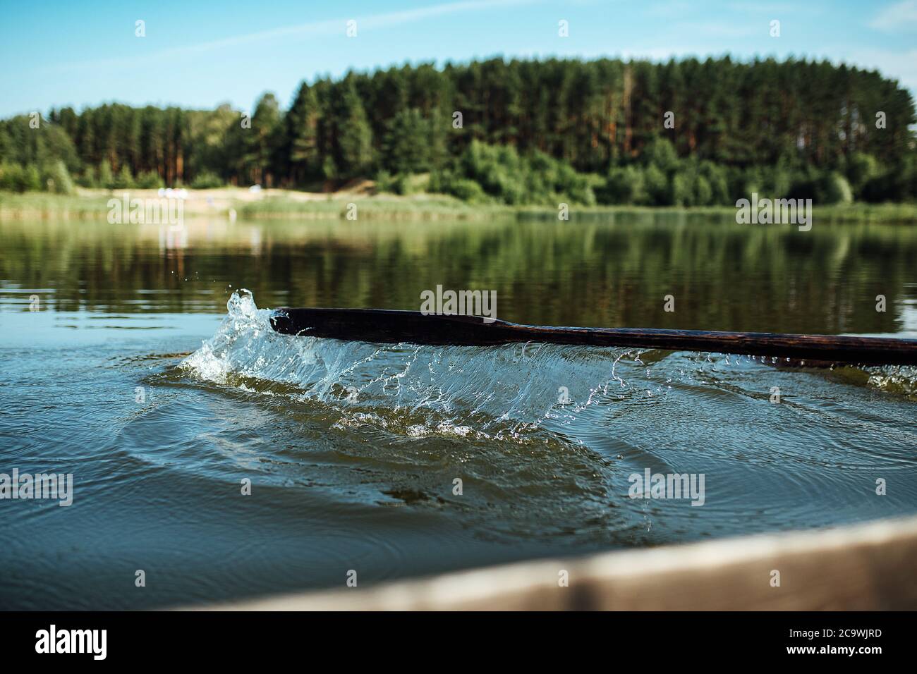 Sportler im Urlaub sind im Rudern beschäftigt, Schwimmer auf hölzernen Rudern schlagen das Wasser, spritzt eine Menge Tropfen herum Stockfoto