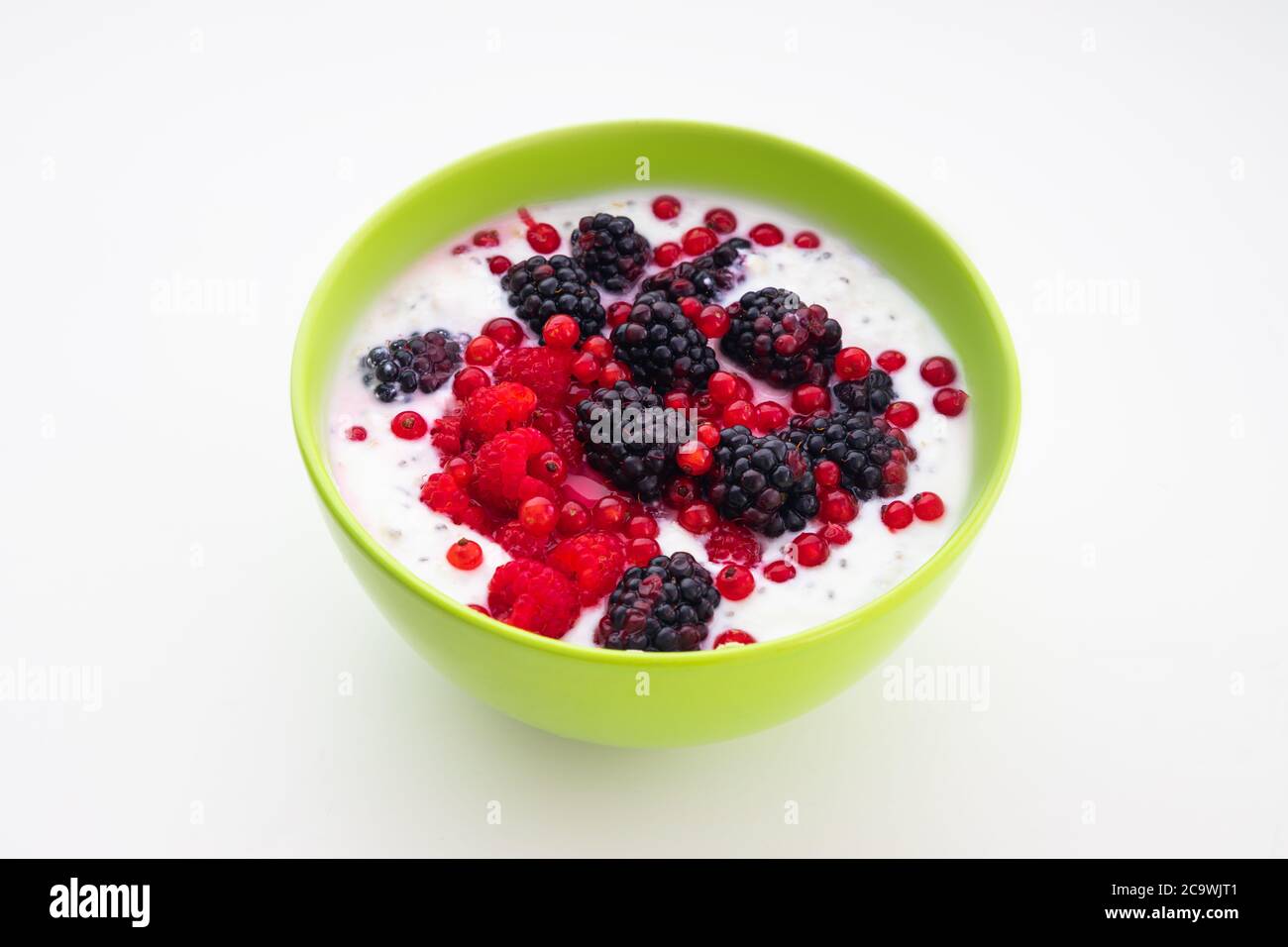 Gesundes Frühstück in einer Schüssel mit Joghurt Milch frisches Obst Erdbeeren, Himbeeren, Brombeeren, Samen und Müsli Stockfoto