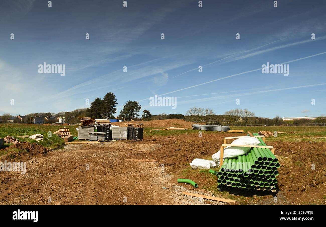 Bridgend, Wales - April 2018: Grüne Entwässerungsrohre und andere Baustoffe auf dem Boden, der für den Bau freigegeben wurde Stockfoto