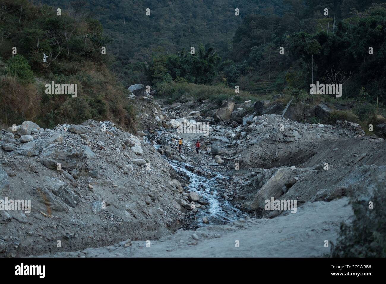 Zwei Männer in bunten Hemden, die Handarbeit an einem Bergfluss voller Felsen von Ngadi, Annapurna Circuit, Nepal, machen Stockfoto