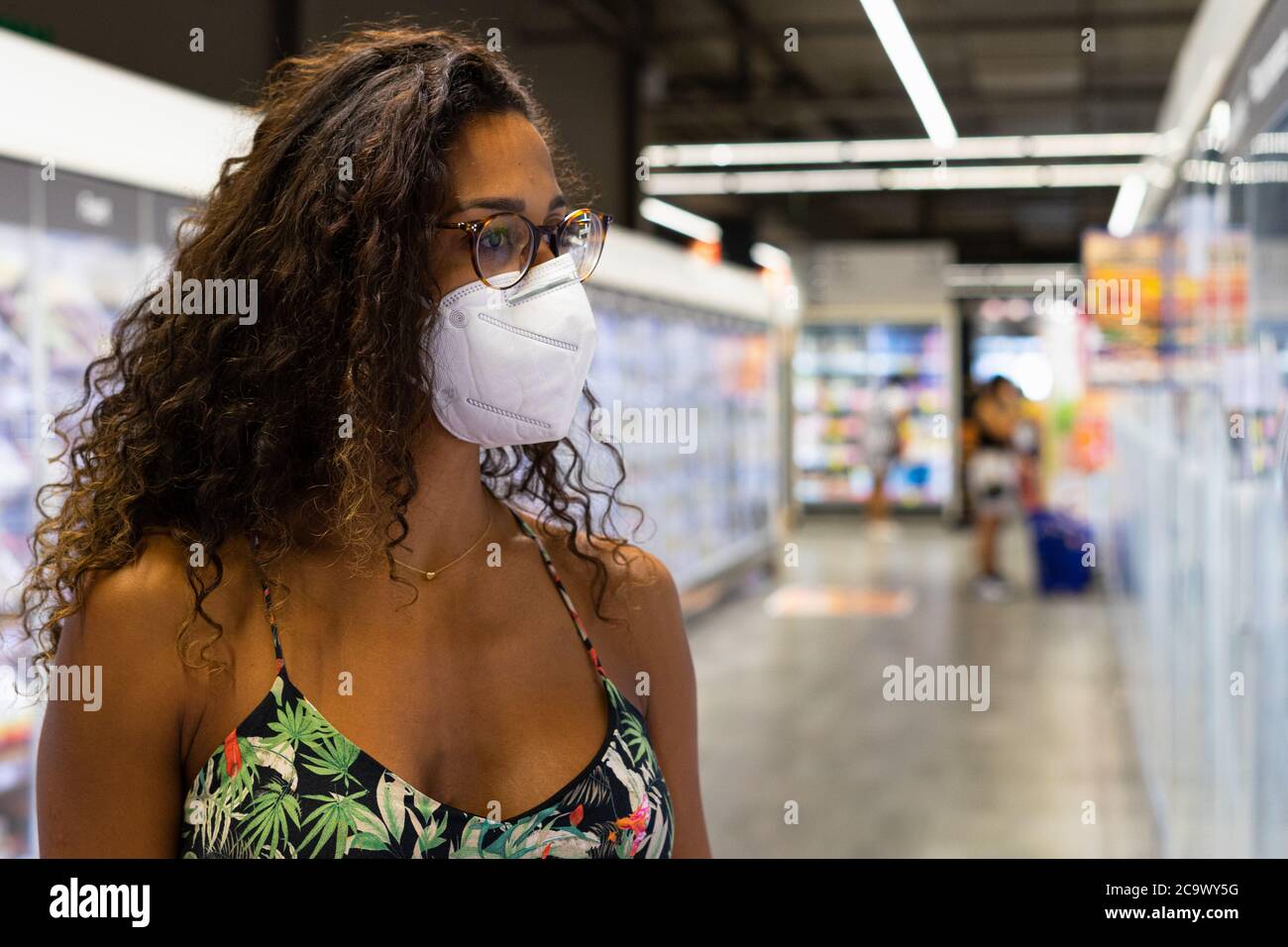 Brasilianische junge Frau einkaufen im Supermarkt mit Maske. Neues Normalitätskonzept. Stockfoto