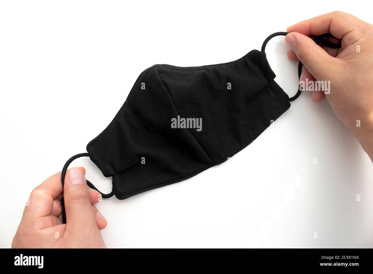 Eine Person, die eine schwarze Gesichtsmaske auf weißem Hintergrund hält Stockfoto