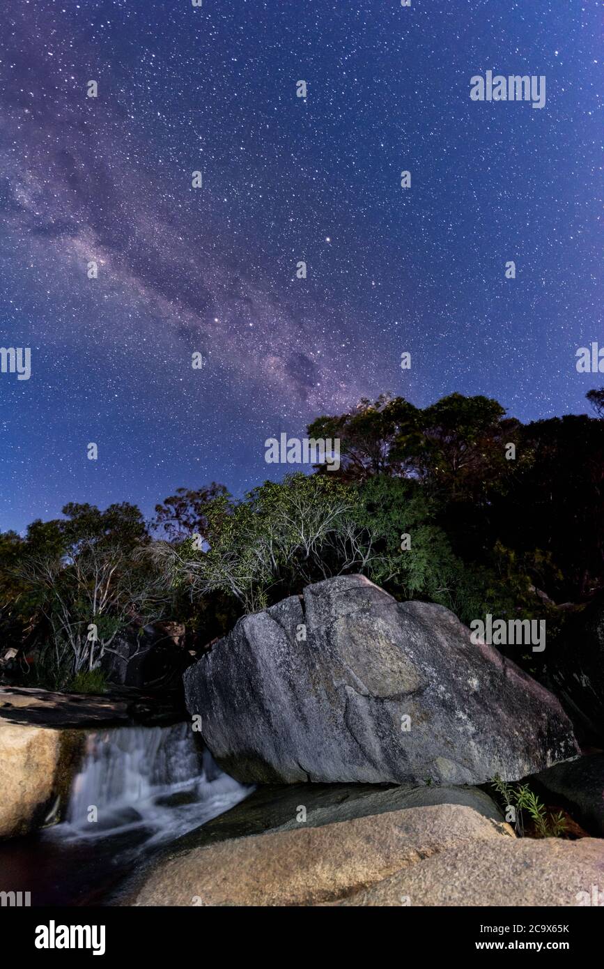 Der Milchstraßenkern, der sich über die lichtbemalte Landschaft der beliebten Touristenattraktion Davies Creek Falls in der Nähe von Mareeba, Queensland, Australien erhebt. Stockfoto