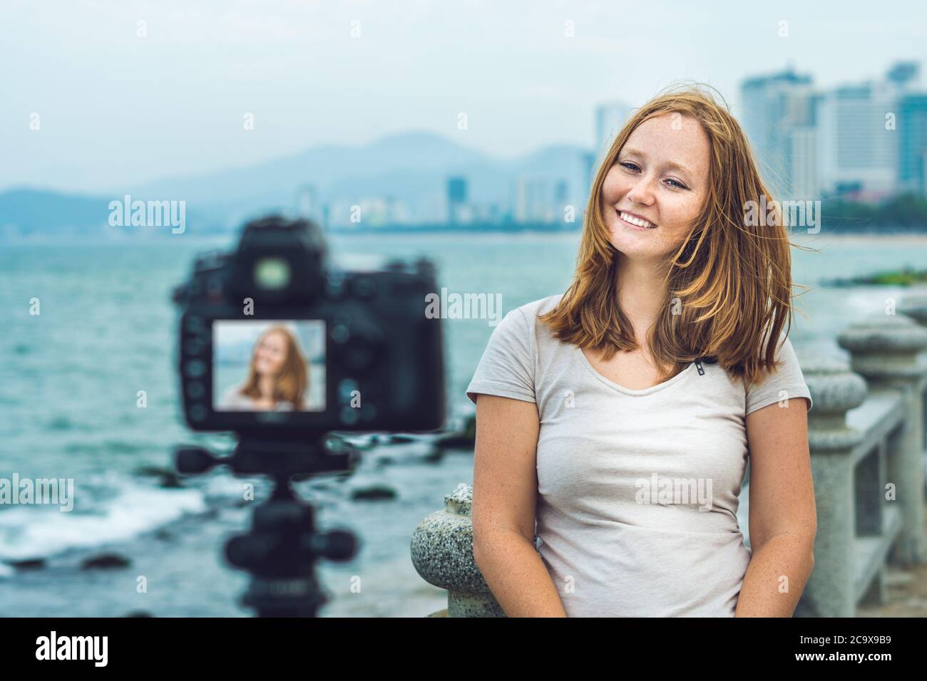 Eine junge Bloggerin führt ihren Videoblog vor einer Kamera am Meer. Blogger-Konzept Stockfoto