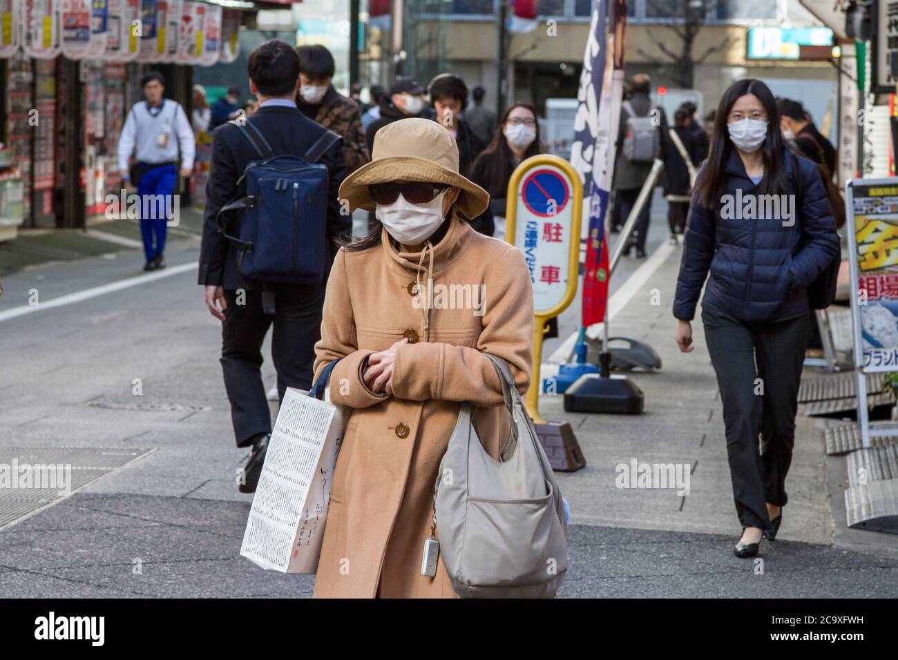 Menschen, die Gesichtsmasken als vorbeugende Maßnahme tragen, gehen inmitten der Coronavirus-Krise auf der Straße. Der zweimonatige Ausnahmezustand, der von der japanischen Regierung als Reaktion auf die COVID-19-Pandemie ausgerufen wurde, endete am 1. Juni. Obwohl Japan die hohen Infektionen und Sterblichkeitsraten einiger Länder während der ersten Krisenwelle vermieden zu haben scheint, wurden in vielen Gebieten in Tokio und im ganzen Land Geschäfte geschlossen und geschlossen. Die Absage der Olympischen Spiele 2020 in Tokio und die zunehmende Zahl von Infektionen, da die Menschen nach der Schließung wieder zu einem normaleren Leben zurückgingen. Eine zweite Welle von Stockfoto