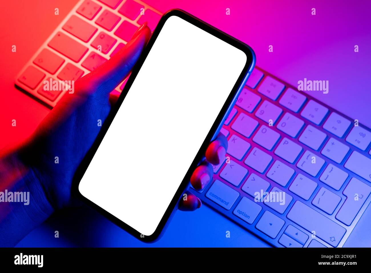 Smartphone Mockup in Frau Hand in blauen und rosa Tönen. Rahmenlose Smartphone-Modell mit leerem weißen Bildschirm. Leeres Leerzeichen für Text. Speicherplatz kopieren. Isolat Stockfoto