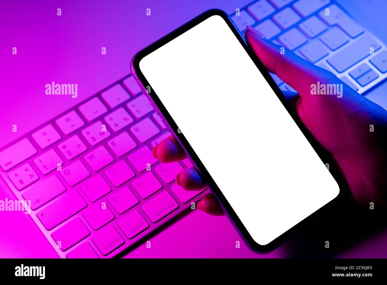 Smartphone Mockup in Frau Hand in blauen und rosa Tönen. Rahmenlose Smartphone-Modell mit leerem weißen Bildschirm. Leeres Leerzeichen für Text. Speicherplatz kopieren. Isolat Stockfoto