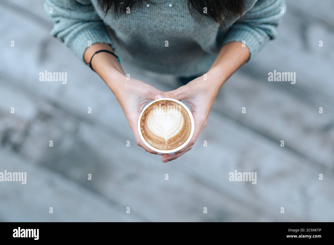 Junge Frau hält Einweg-Tasse mit herzförmigen Kaffee in einem Café. Hochwertige Fotos Stockfoto
