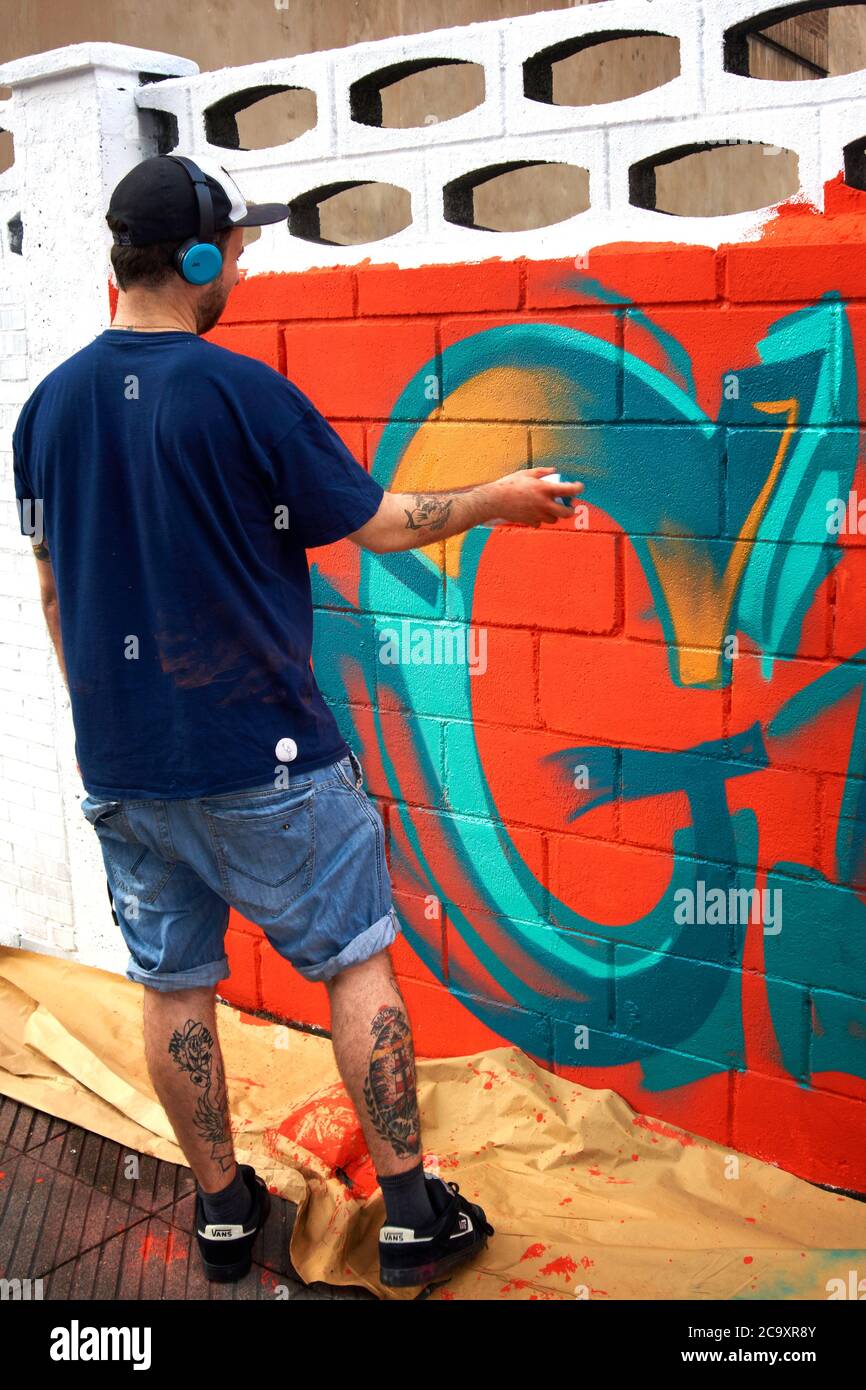 Straßenkünstler malt ein buntes Graffiti an einer weißen Wand Stockfoto