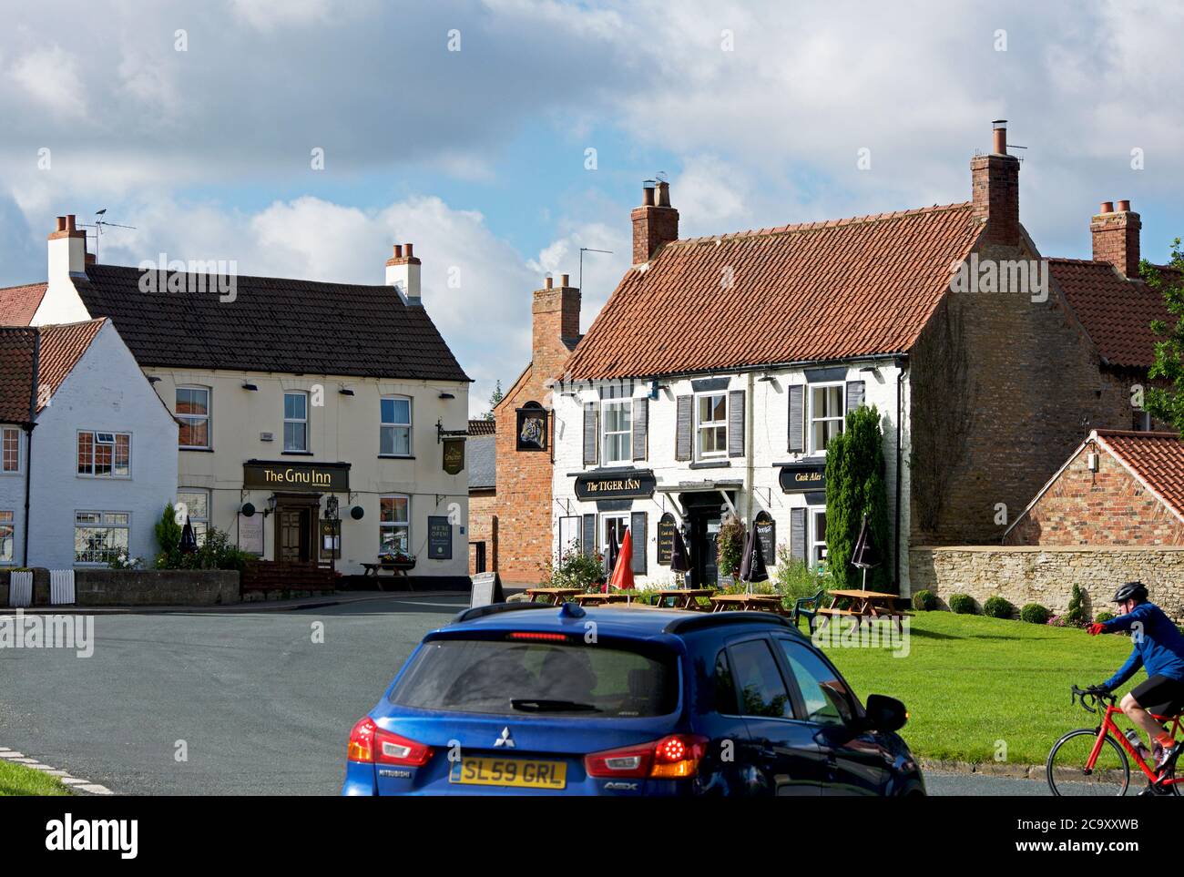 Auto und Radfahrer im Dorf North Newbald, East Yorkshire, England Stockfoto