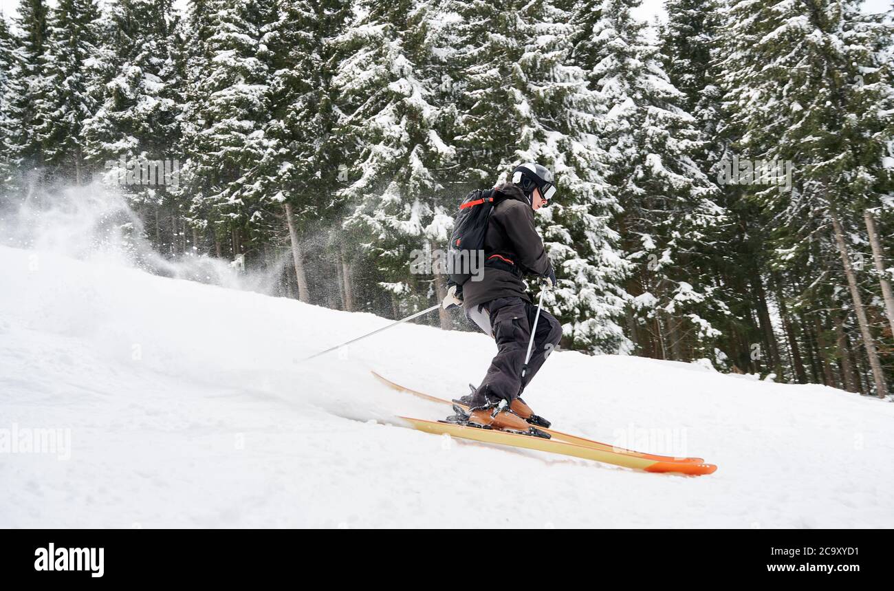 Seitenansicht Momentaufnahme des Skifahrers, der die Piste entlang des Fichtenwaldes abfährt. Gleichgewicht auf Schnee halten. Konzept der extremen Winter Arten von Sport. Saisonunterhaltung Stockfoto
