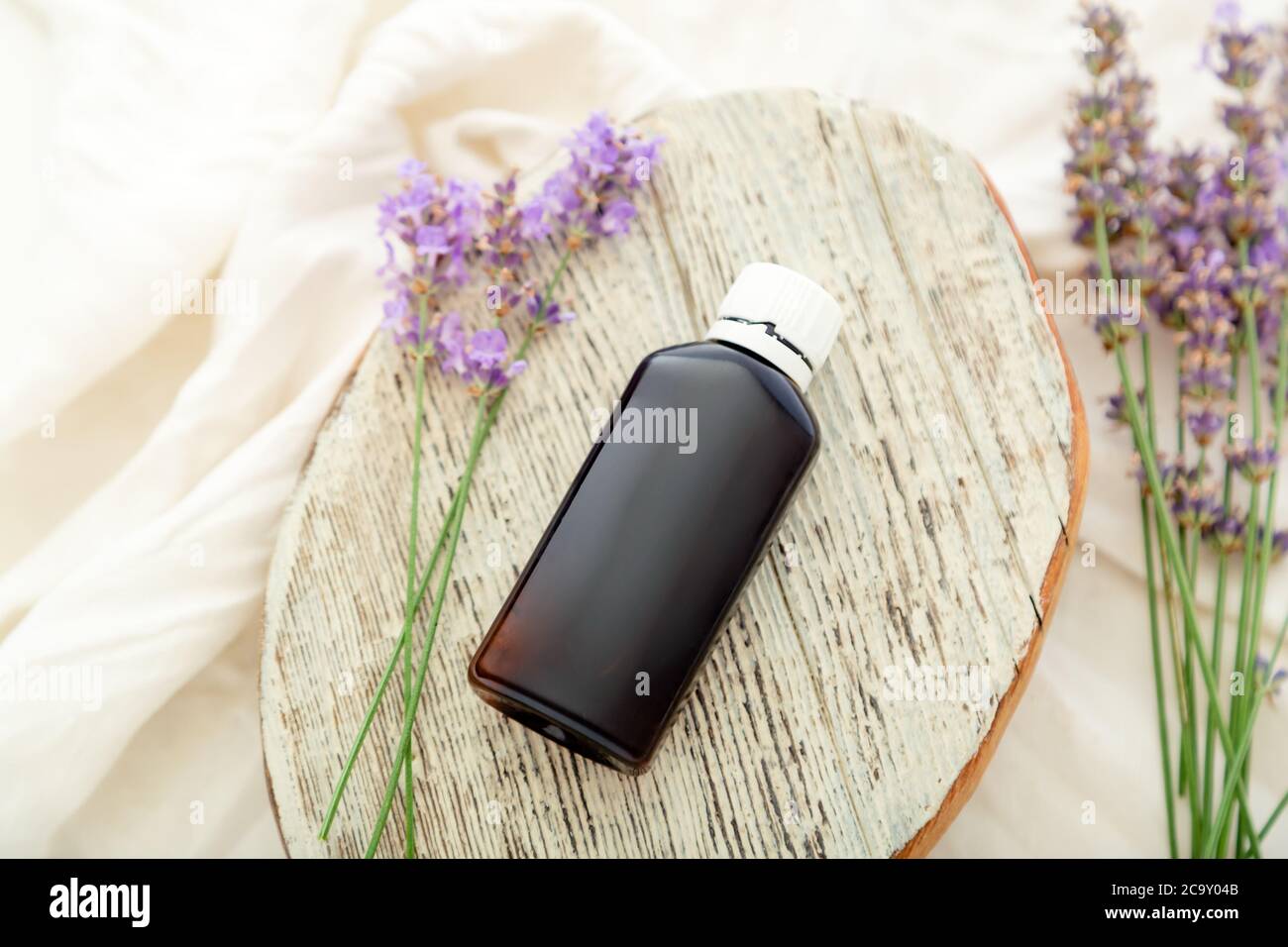 Lavendelblüten mit Lavendel ätherisches Öl Flasche auf weißem Holz rustikalen Brett und Stoff. Aromatherapie-Behandlung, natürliche Bio-Spa-Kosmetik Stockfoto