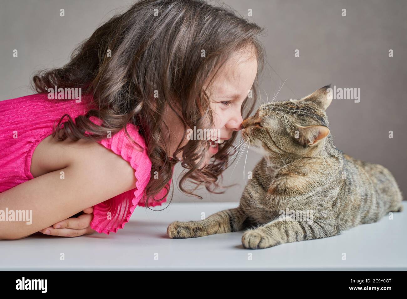 Kid girl mit Kätzchen auf dem Bett liegen, lachen, spielen mit Katze. Lifestyle Kinderfoto. Stockfoto