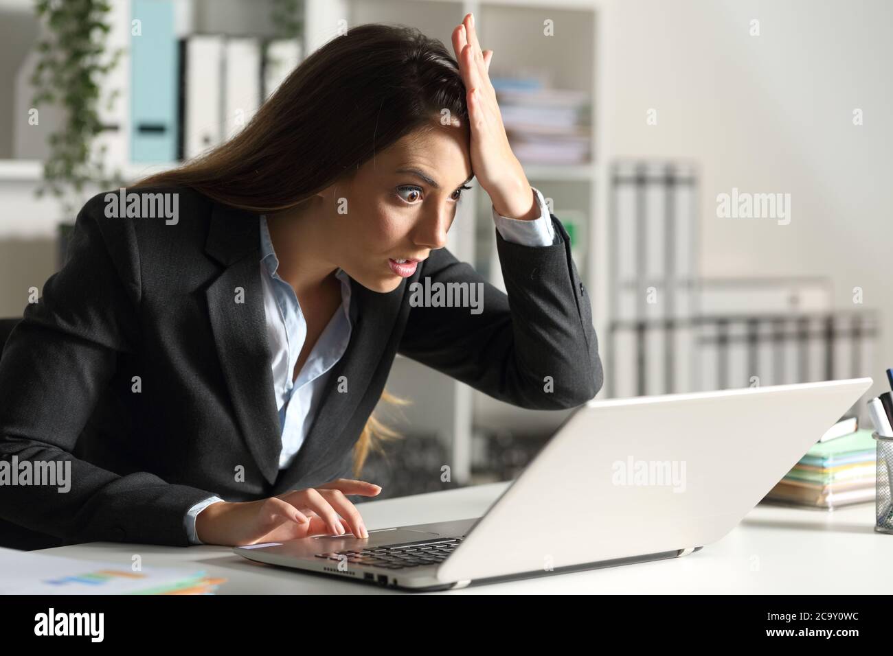 Ich war überrascht, dass eine Frau, die im Büro auf einem Schreibtisch saß, einen Fehler am Laptop entdeckte Stockfoto