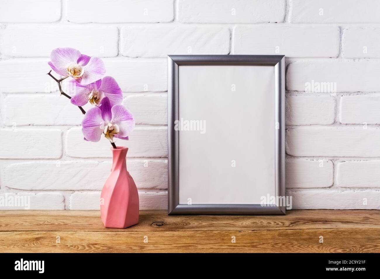 Silberner Rahmen Mockup mit rosa Orchidee in der verdrehten Vase. Leerer Rahmen für Präsentationsgrafiken. Schablonenrahmen für moderne Kunst Stockfoto